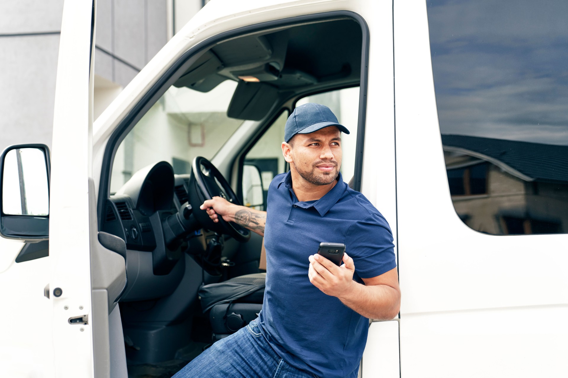 Delivery person with mobile phone gets out of the car